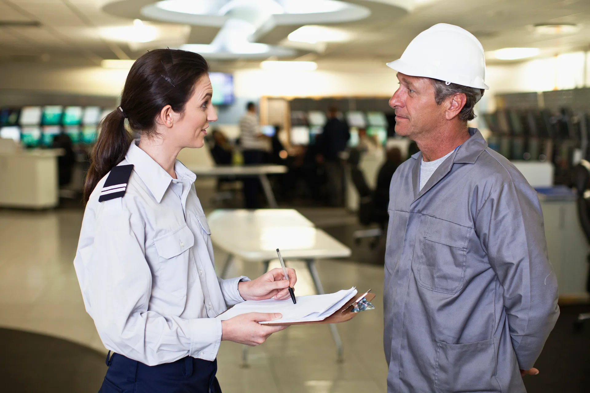 A uniformed colleague speaking with a professional in a hard hat